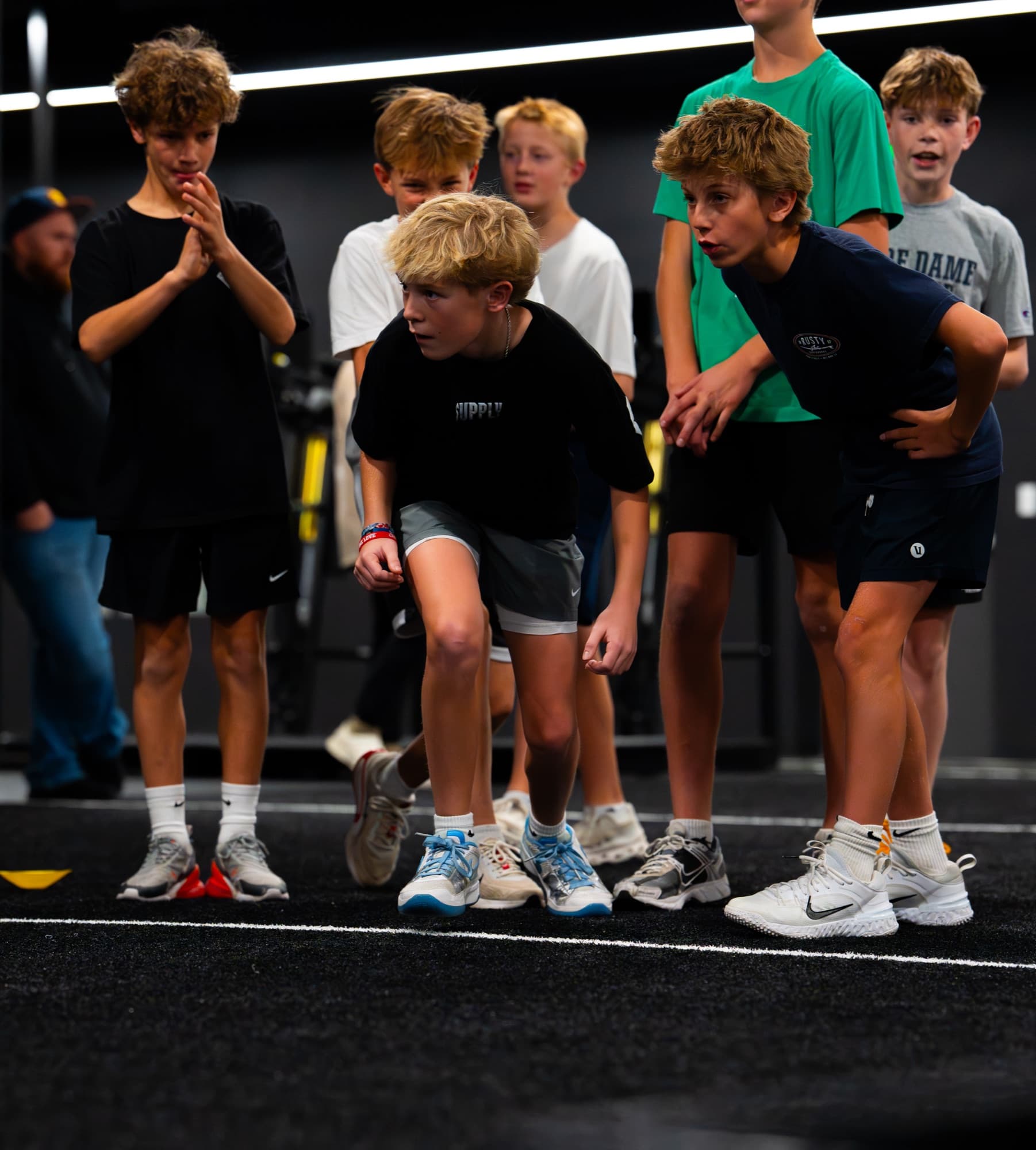 Young athletes crouched at the start line during an indoor training session
