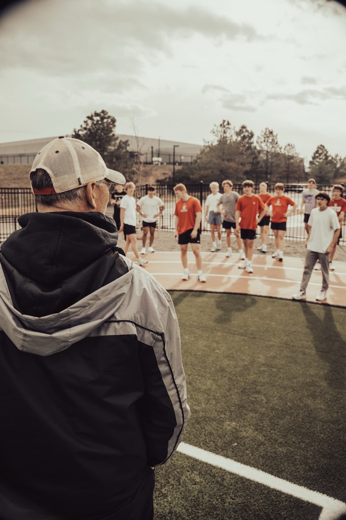 A coach addressing a group of athletes on a turf field